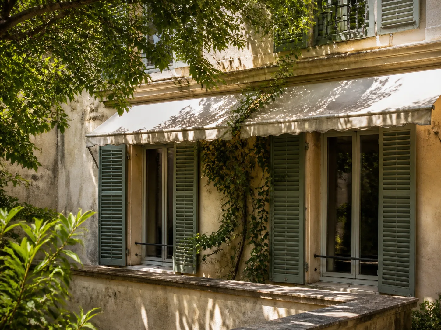 Façade ensoleillée protégée par volets, auvent et végétation