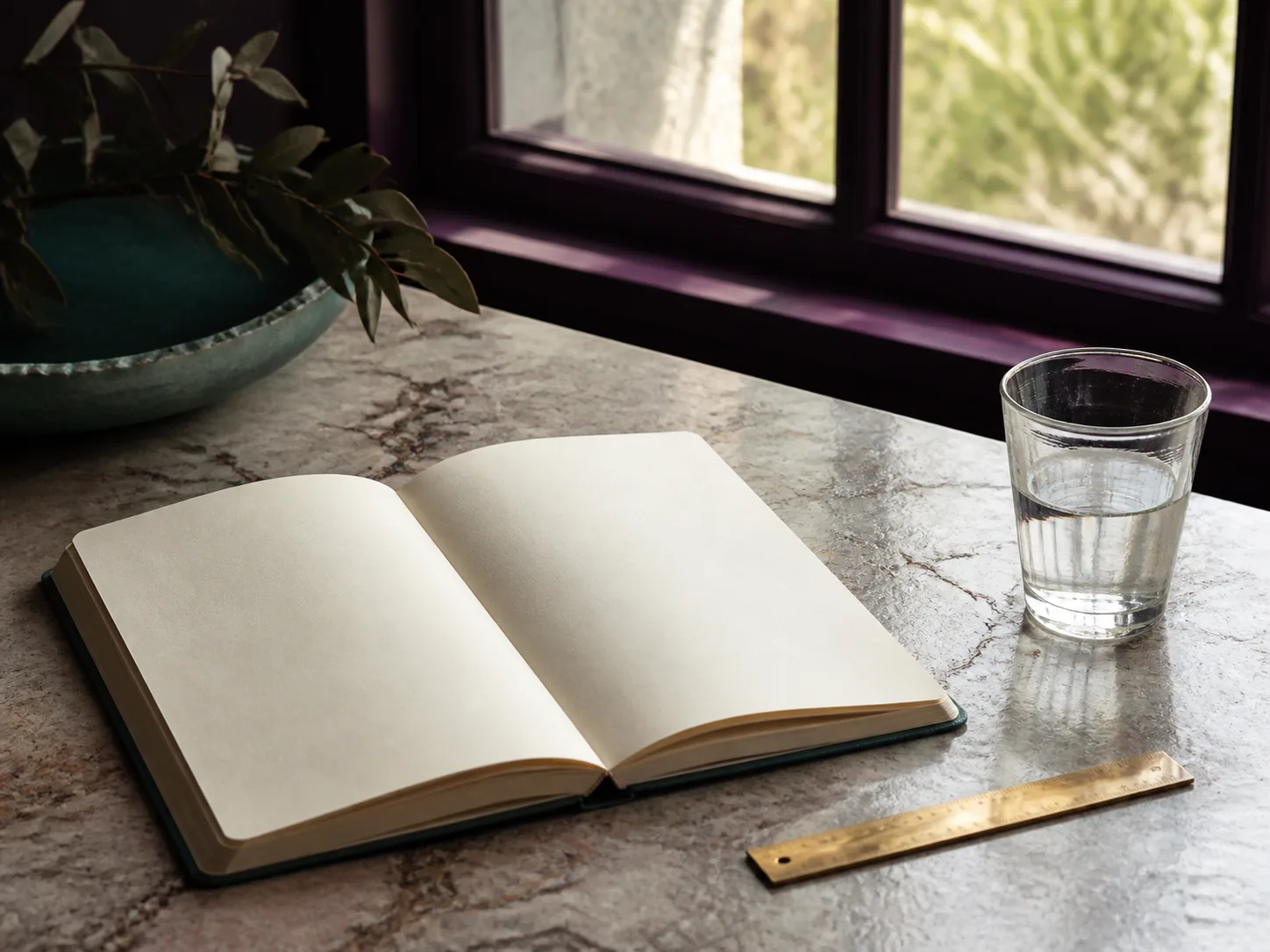Carnet ouvert, verre d'eau et règle dorée